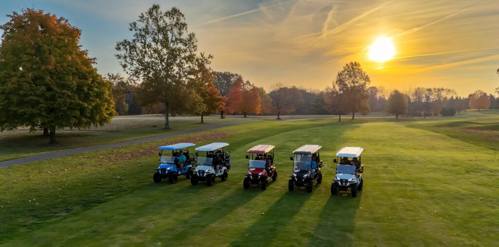 Five-Wintao-EV-golf-carts-in-various-colors-lined-up-on-a-sunlit-golf-course